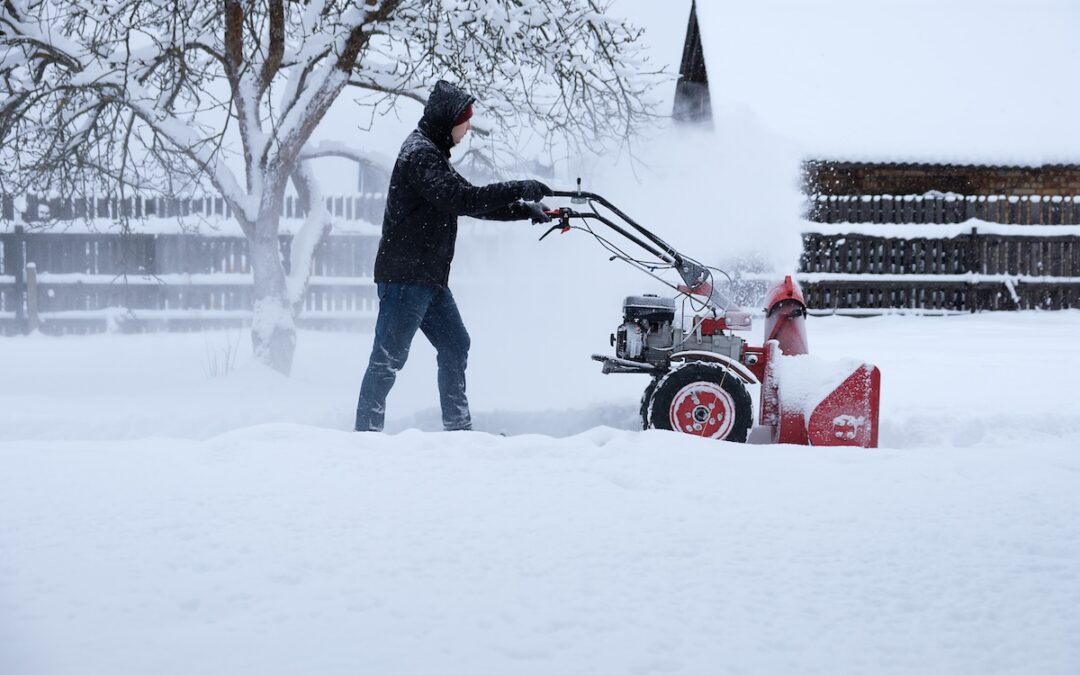 a young man clearing snow in his backyard with wheeled snow blower