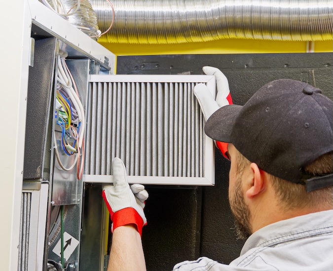 HVAC service technician changing dirty air filter in the central ventilation system. Change filter in rotary heat exchanger recuperator. Air duct ventilation system maintenance for clean air.