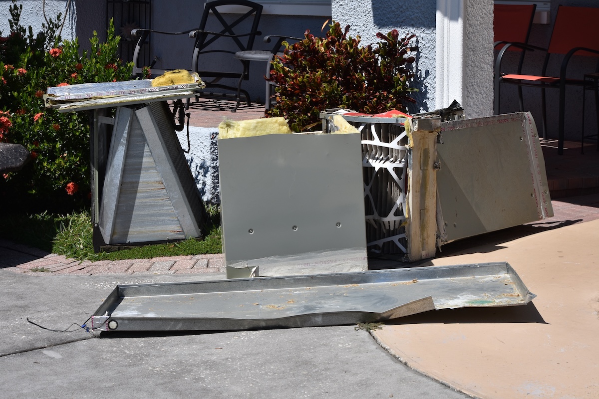 Discarded parts of a replaced furnace sit outside a residence