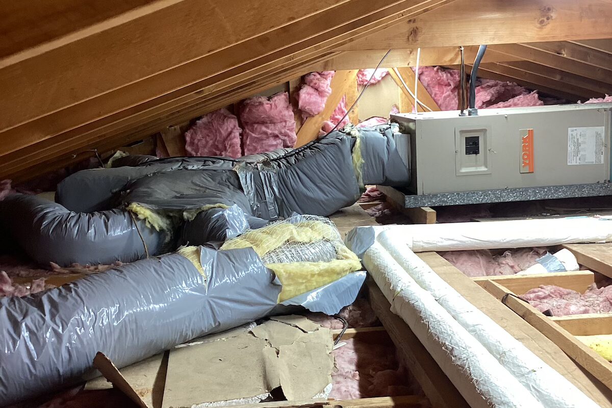 An attic crawlspace area containing exposed, damaged ductwork for a residential HVAC repair.
