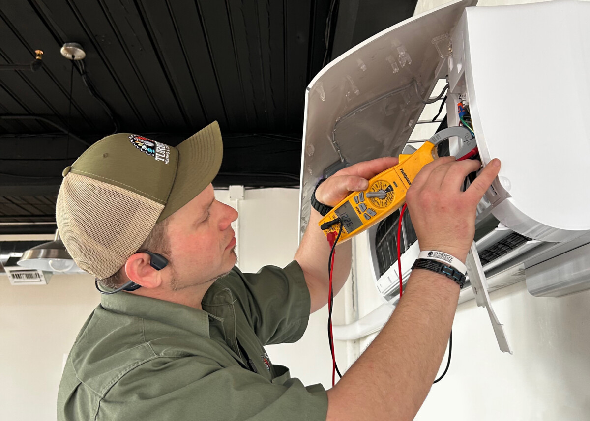 Turkey Heating & Cooling technician Roland works on a ductless minisplit cooling system.