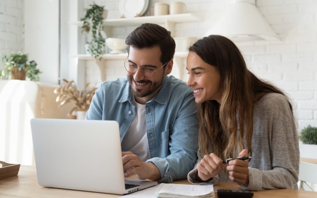 Happy young couple paying bills online in computer app